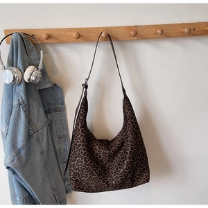Close-up of leopard print suede hobo bag hanging with adjustable shoulder strap detail