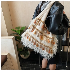 Détail du sac cabas bohème en tricot avec des pompons colorés et sangles dorées