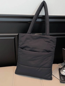 Fashionable black quilted puffer tote bag with spacious interior and padded shoulder straps