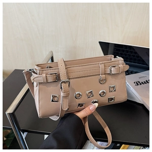 Detail of light brown patent leather bag with metal eyelets and decorative buckles