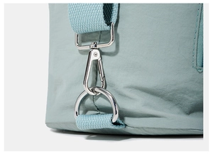 Detail of grey-green nylon tote bag featuring silver metal clasps and woven strap