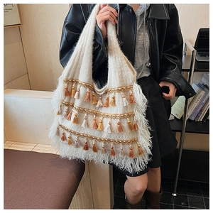 Détail du sac cabas en tricot blanc avec glands bohèmes et plumes sur veste en cuir