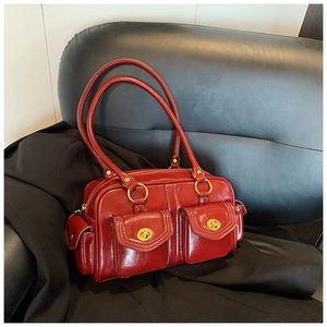 Detail of red vintage boston bag with glossy oil wax leather and gold buckle hardware