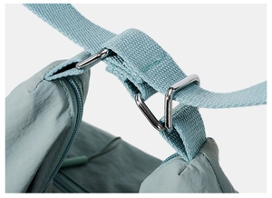 Detail of light blue nylon tote showing woven strap and silver metal buckle connection