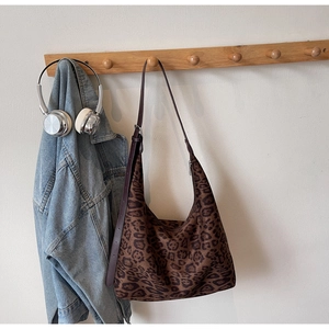 Detail of leopard print hobo bag hanging on hook with adjustable brown shoulder strap