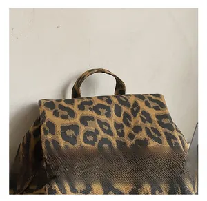 Detailed close-up of leopard print canvas backpack with red embroidery and sturdy handle