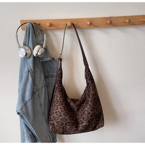 Close-up of leopard print hobo bag texture with leather strap on a wooden hanger