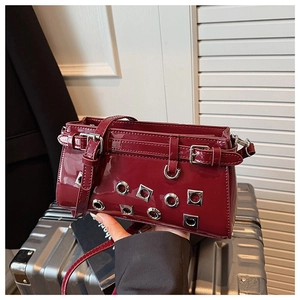 Detail of burgundy patent leather bag with silver rivets and punk style hollow accents