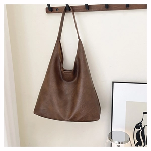 Detail view of large brown hobo bag in matte leather hanging on a wooden hook