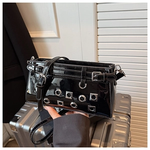 Detailed close-up of glossy black patent leather bag with silver metal eyelets and buckles