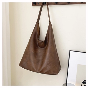 Close-up of caramel brown tote bag with leather texture hanging on a wooden hook