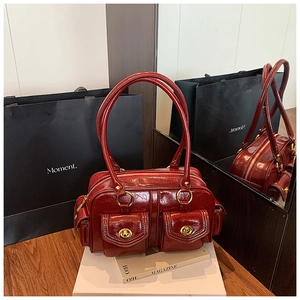 Detailed view of glossy burgundy leather bag with gold buckles and dual front flap pockets