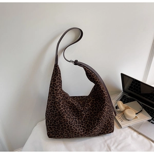 Close-up of leopard print hobo bag with adjustable brown strap on a white workspace