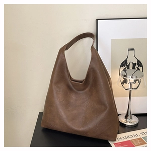 Detail view of large dark brown tote bag with matte leather texture in minimalist setting