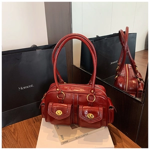 Close-up of vintage dark red leather boston bag with gold twist locks and shiny finish