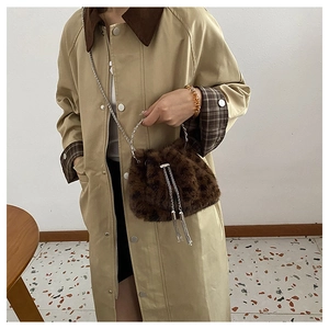 Detail of plush brown bucket bag with silver metal ring handle and chain strap