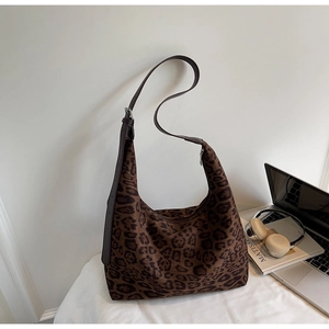 Close-up of leopard print tote bag with brown leather strap and side-view detail