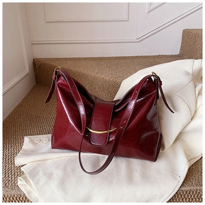 Détail du sac en cuir brillant bordeaux avec une boucle métallique dorée élégante
