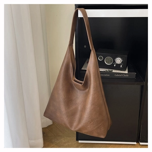 Close-up of brown hobo bag featuring vintage leather texture and wide integrated shoulder strap