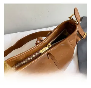 Close-up of golden zipper hardware and leather grain on brown shoulder bag