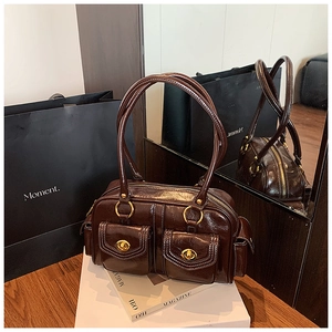 Detail of dark brown glossy leather shoulder bag featuring gold twist-lock double pockets