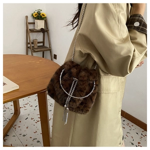 Detailed view of brown faux fur bucket bag with silver chain strap and metallic tassel