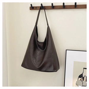 Close-up of deep brown glossy leather tote bag hanging on a minimalist wooden hook