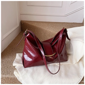 Détail d'un grand sac cabas rouge foncé brillant avec garniture métallique dorée chic