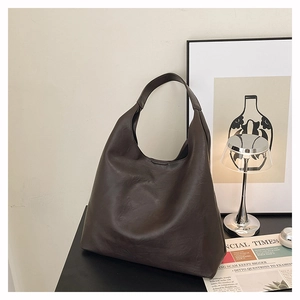 Detail view of large dark brown hobo shoulder bag in a minimalist indoor setting