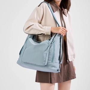 Detail of multi-pocket foggy blue nylon tote showing spacious storage and wide strap