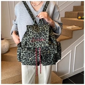 Detailed close-up of leopard print canvas backpack with drawstring and red brand embroidery