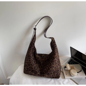 Detailed close-up of large leopard print tote bag with brown leather shoulder straps