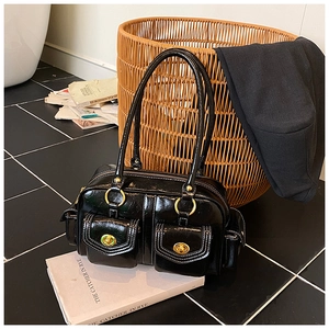 Detail of glossy black leather bag featuring double front pockets and gold turn-locks