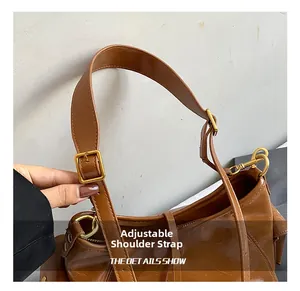 Detail of adjustable shoulder strap with gold metal buckle on a brown tote bag