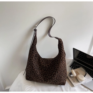 Close-up of leopard print hobo bag next to art books and lifestyle office props