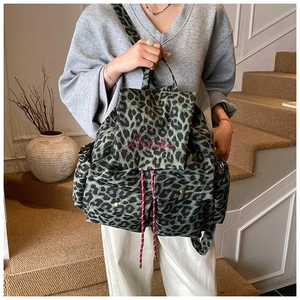 Detail of green leopard canvas backpack with red script embroidery and drawstring
