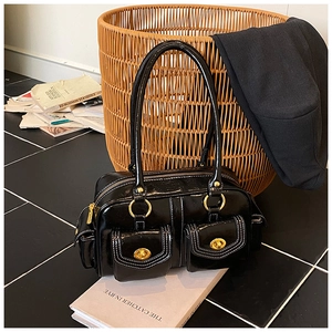Detail of glossy black leather shoulder bag with gold turn-lock pockets and hardware
