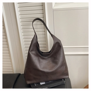 Detailed view of the dark brown textured faux leather tote bag on a modern seat