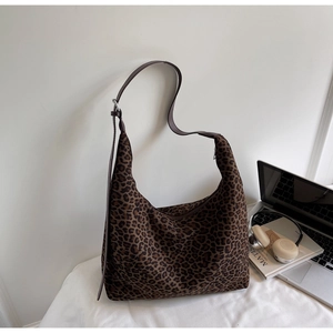 Detailed view of large leopard print tote bag with brown straps in a lifestyle office setting