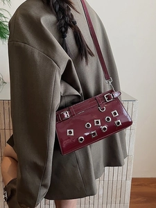 Dark red patent leather crossbody bag with punk style silver eyelets and buckle accents