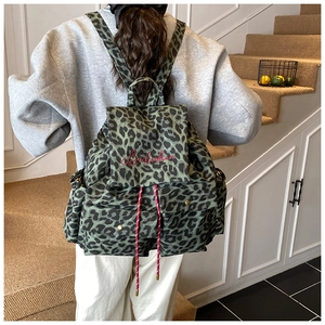 Macro detail of leopard print canvas backpack with drawstring closure and red embroidery