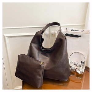 Macro shot of dark brown faux leather tote with textured folds and gold zipper detail