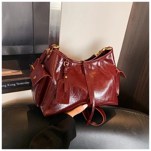 Detail of burgundy glossy patent leather tote bag with vintage crinkle texture and gold hardware