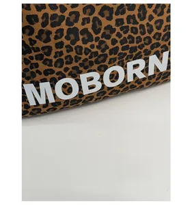 Détail du tissu en toile léopard avec lettrage blanc MOBORN sur le sac cabas