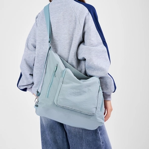 Detail of light blue oversized messenger bag with waterproof fabric and wide strap