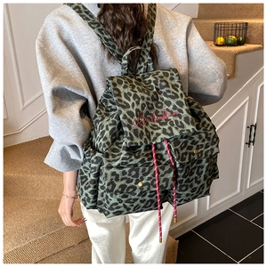 Detailed view of leopard print canvas backpack with red embroidery and drawstring toggle