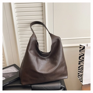 Detail view of large dark brown leather tote bag with vintage texture and wide shoulder strap
