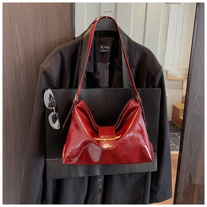 Détail du sac cabas en cuir verni bordeaux avec texture brillante et boucle dorée