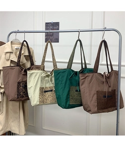 Detail of four colorful suede leopard print tote bags hanging in a stylish display