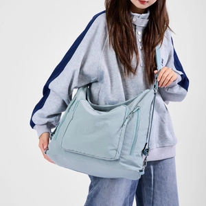 Detail of light blue nylon tote bag showing multiple zipper pockets and adjustable strap
